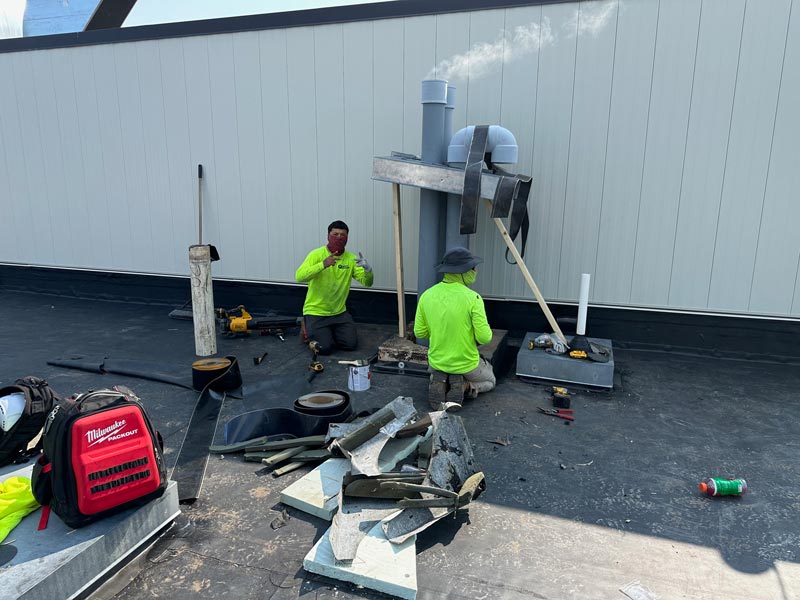 Quality Roofing crew working with sheet metal on a commercial roof